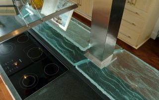 contemporary coastal kitchen design detail. Custom design glass shelf around columns over cooktop