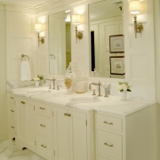 Master bathroom double sink vanity with marble floor tile and counter top. White painted wood wall paneling, recessed lighting and sconces for layered lighting plan