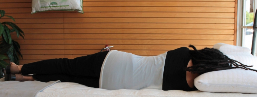 Person laying down on a memory foam mattress to test spine alignment and comfort.