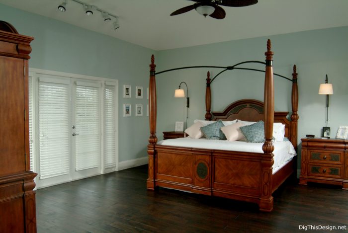 Transitional coastal style bedroom with dark walnut wood floors, wood post bed, light blue walls and minimal decor.