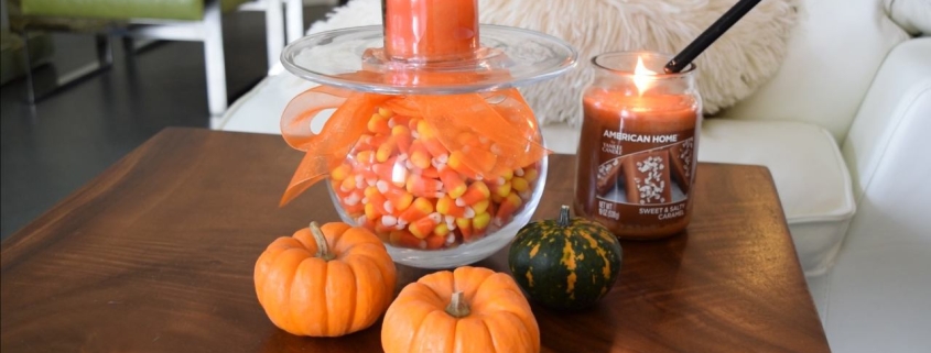 Living room wood slab table with DIY Halloween decor project. Glass vase wrapped in orange tulle ribbon holding candy corn next to tiny fresh pumpkins and squash with American Home by Yankee Candle fragrances