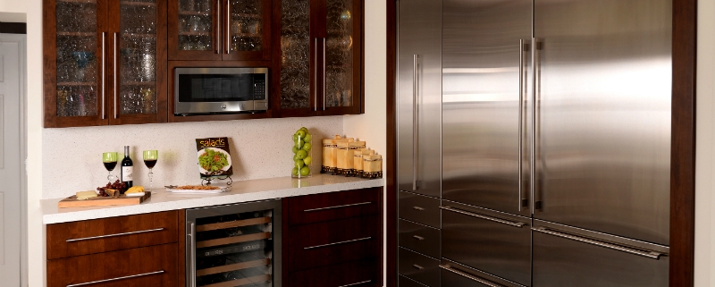 contemporary kitchen wine bar with microwave mounted in wall cabinet shelf, water texture glass cabinet doors, sub zero refrigerators and wine cooler