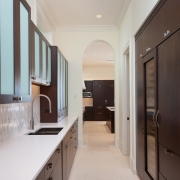 contemporary barbados style kitchen butler's pantry with dark cabinetry and white counter tops