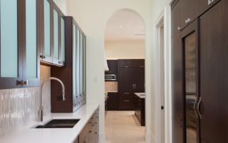 contemporary barbados style kitchen butler's pantry with dark cabinetry and white counter tops