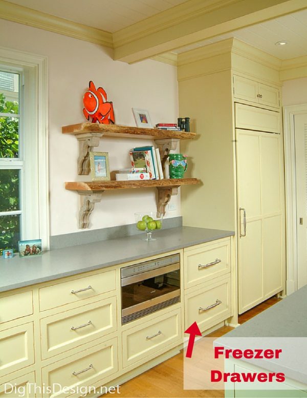 coastal transitional style open kitchen floor plan with yellow painted cabinetry live edge wood shelves and freezer drawers