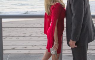 Couple on Valentine's Day, wearing red dress from Sabre Mochachino and silver accessories on the beach