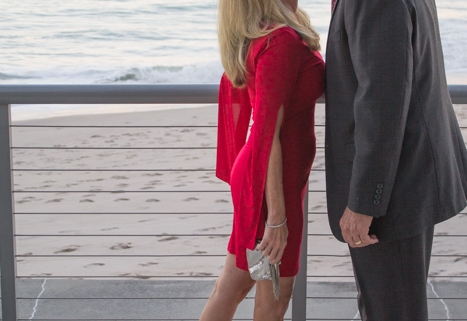 Couple on Valentine's Day, wearing red dress from Sabre Mochachino and silver accessories on the beach