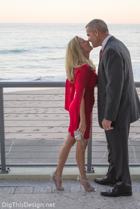 Couple on Valentine's Day, wearing red dress from Sabre Mochachino and silver accessories on the beach