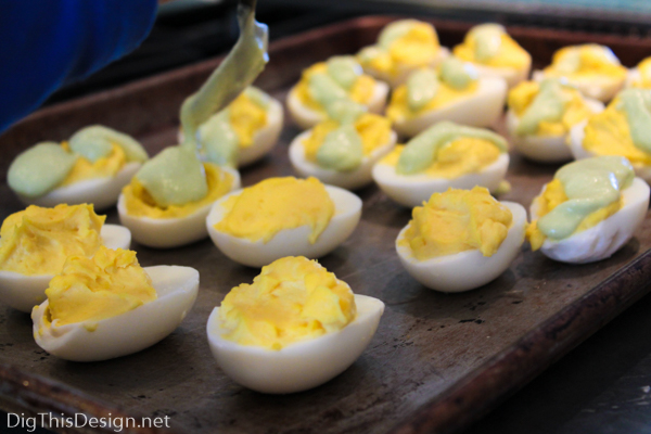 Topping devilled eggs with green avocado drizzle for a St. Patrick's Day party. 