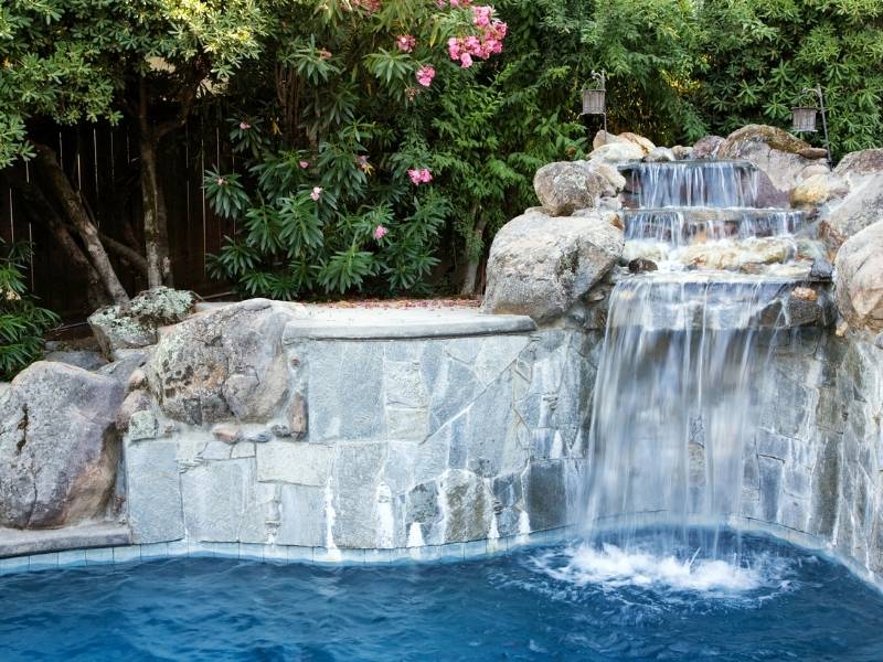 6 Easy Steps to a Beautiful Outdoor Living Space - Backyard pool with stone water falls.