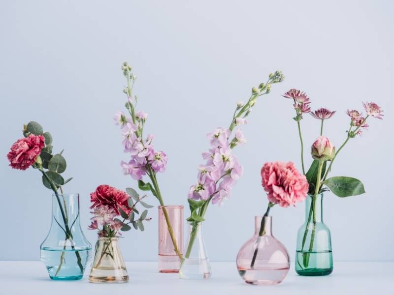 Flowers in glass vases of blue, pink and green