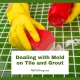 Dealing with Mold on Tile and Grout - scrubbing a green tile counter in yellow gloves and red sponge.