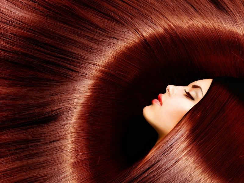 Woman with long sleek straight red flowing hair.